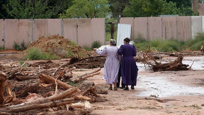 Two woman walk amongst debris left behind after a flash flood on September 15, 2015 in Hildale, Utah. Flash floods from heavy rains on the afternoon of September 14, 2015 washed away two cars in Hildale