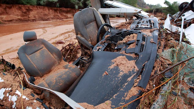 The twisted wreckage of one of two vans that were washed away in a flash flood with women and children inside rest on the bank of Short Creek on September 15, 2015 in Hildale, Utah. Flash Floods from heavy rains on the afternoon of September 14, 2015 washed away two vans in Hildale as they were crossing a flooded creek, killing 13 people.