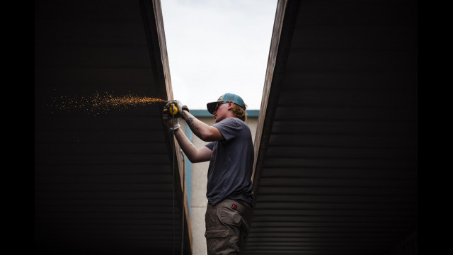 Logan Woodburn works on grinding the edges on a shipping container at Maloy Mobile Storage in Albuquerque, N.M., on Tuesday, Sept. 13, 2022. Pat and Mary Beth Maloy established their business in 1988 and specialize in custom modifying and manufacturing storage containers for government and commercial use. (Chancey Bush/Albuquerque Journal)