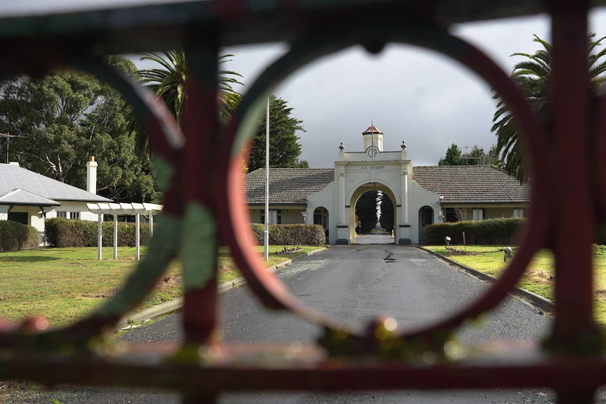 Looking through the circular features of a gate towards a white building once used for fire fighter training