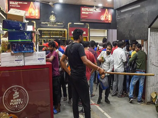 People buy liquor at a store at Azadpur area, in New Delhi