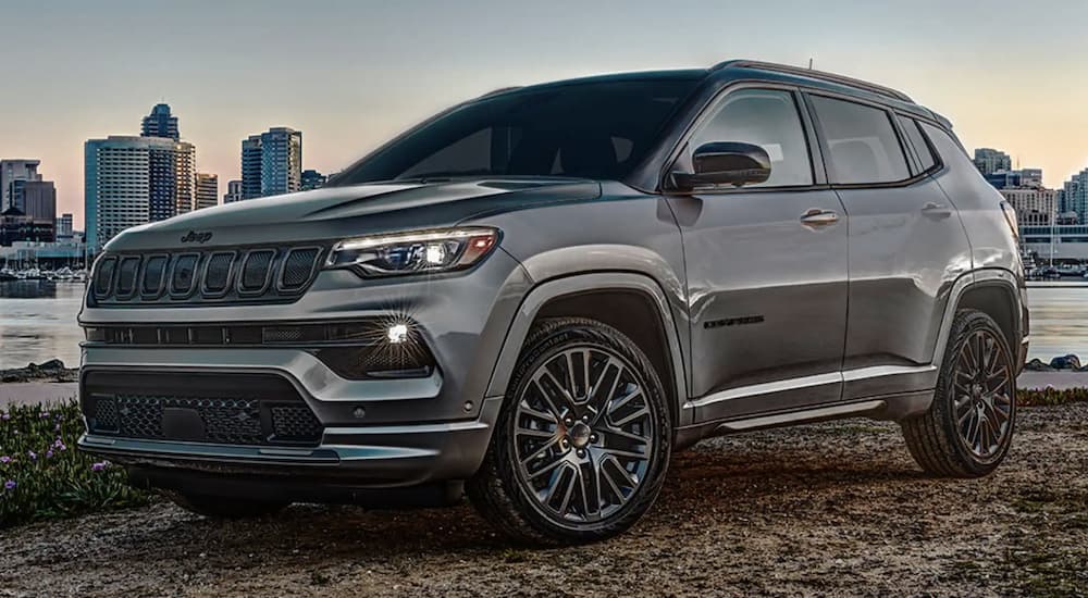 A grey 2022 Jeep Compass is shown from the side parked in front of a city.