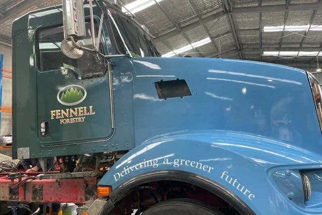 Side view of a blue truck, front end with door and hood dominating the composition.