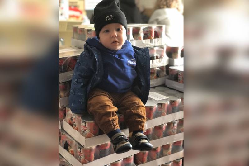 A baby from Kremenchuk sits on top of a pallet of baked beans.
