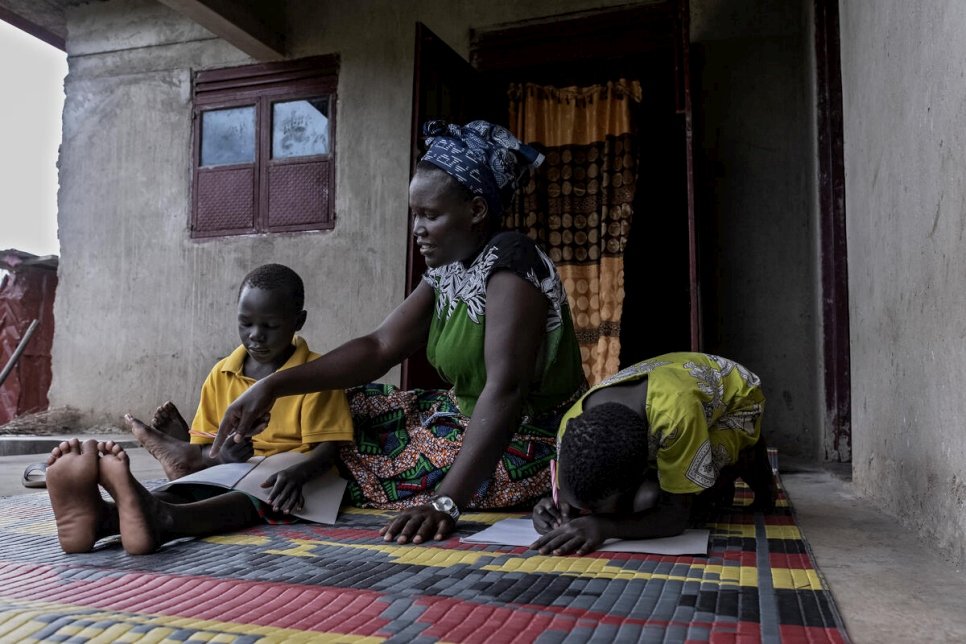 Rose assists her son and niece with their studies at their home in Magwi. 