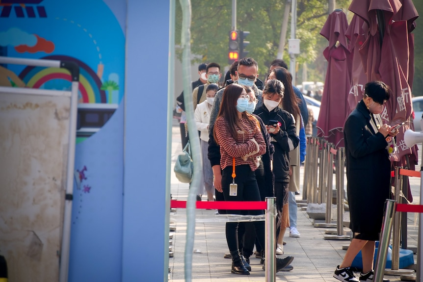 A line of people, all wearing masks 