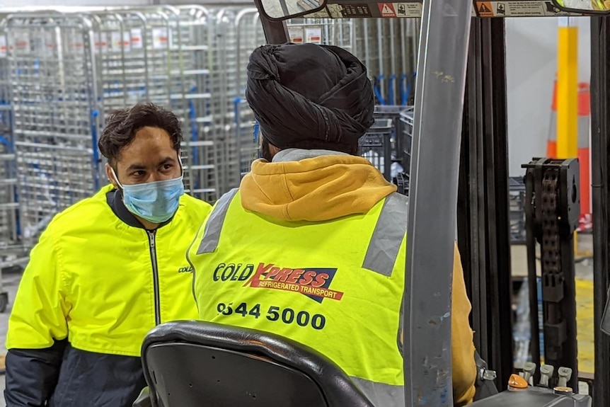 two men in hi vis in a warehouse with covid masks