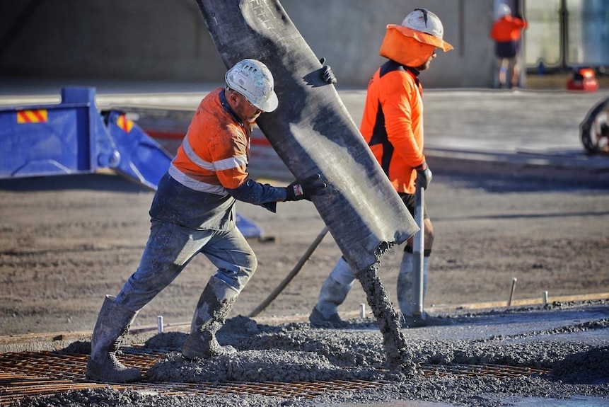 worksite showing a construction worker pouring cement