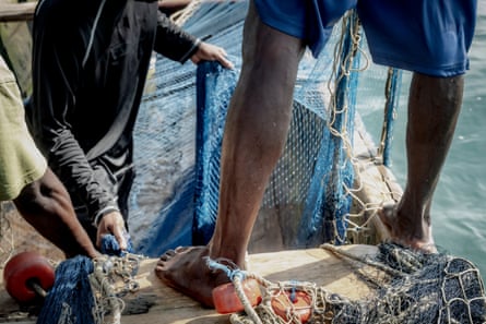 Men work on the nets on a boat out at sea.