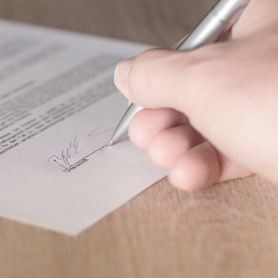 A hand signing a paper document