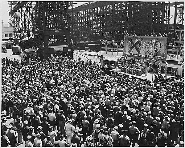 The AJC Band, from Hamilton Field, plays at a war bond rally held at Mare Island on June 26, 1945. Behind the band, caricatures of Mussolini and Hitler have been crossed out and a fanged Japanese figure is labeled "Tough One To Go." (Photo: military-history.fandom.com/wiki)