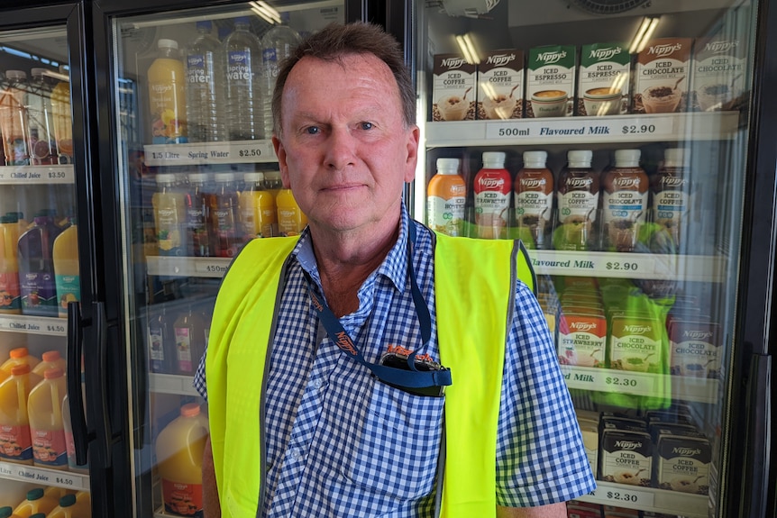 Jeff Knispel wears high vis and stands in front of a drinks fridge.